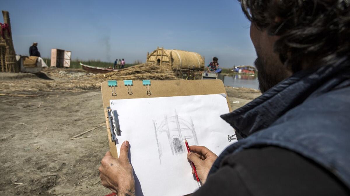 A tourist sketches a drawing of a palm reed-woven house in the marshes of the southern Iraqi district of Chibayish in Dhi Qar province, about 120 kilometres northwest of the southern city of Basra, on March 29, 2019. Hussein FALEH / AFP