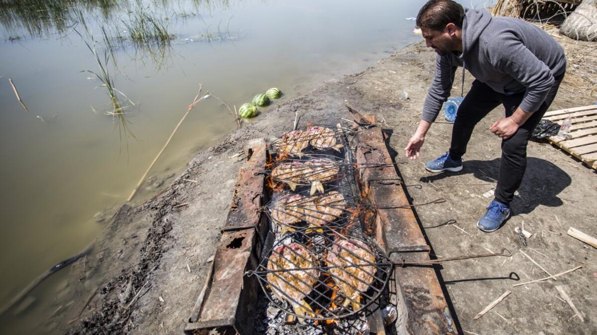 An Iraqi tourist grills fish by the marshes of the southern district of Chibayish in Dhi Qar province, about 120 kilometres northwest of the southern city of Basra, on March 29, 2019. Hussein FALEH / AFP