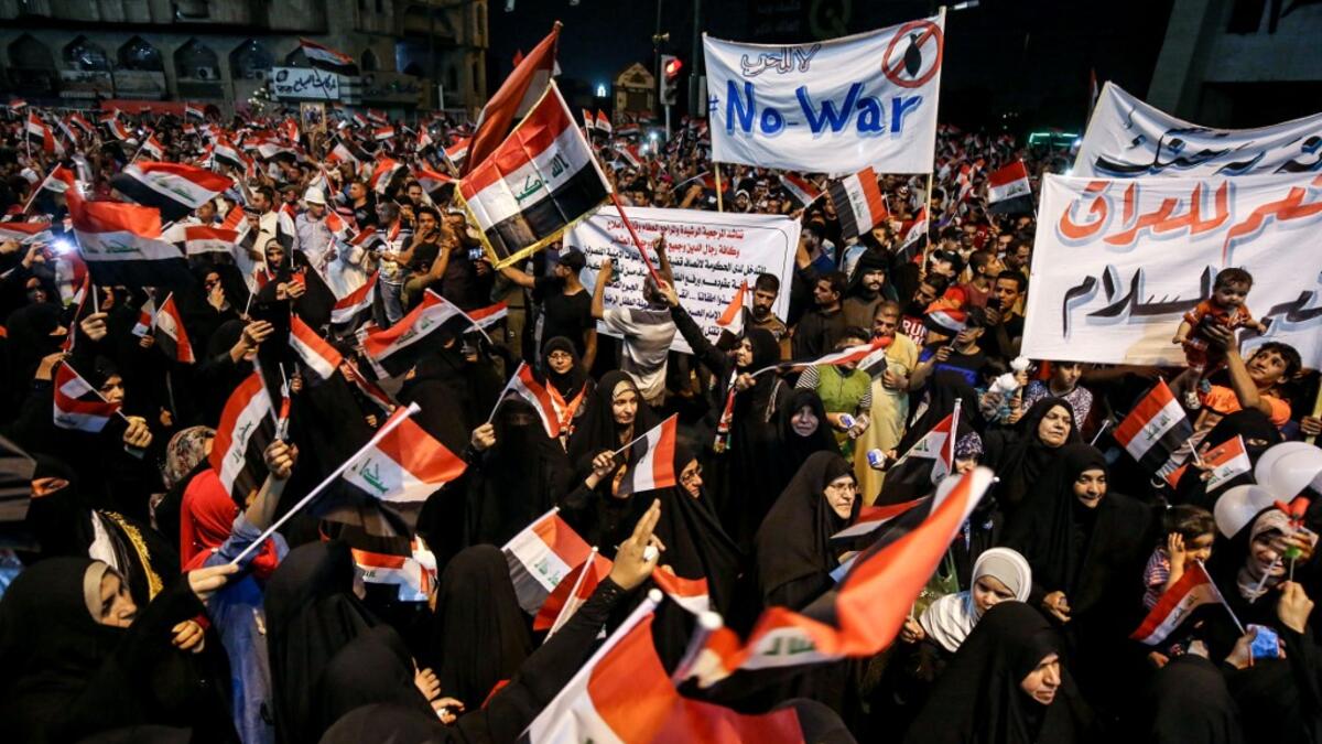 Iraqi followers of Shiite Muslim cleric Moqtada al-Sadr wave national flags and raise protest signs as they demonstrate in the capital Baghdad's central Tahrir Square late on May 24, 2019, against involvement in any conflict between Iran and the United States.  AHMAD AL-RUBAYE / AFP