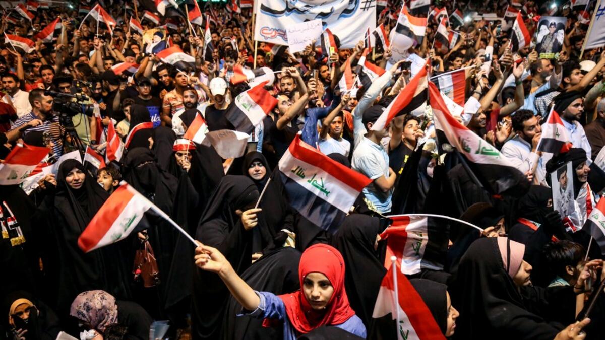 Iraqi followers of Shiite Muslim cleric Moqtada al-Sadr wave national flags and raise protest signs as they demonstrate in the capital Baghdad's central Tahrir Square late on May 24, 2019, against involvement in any conflict between Iran and the United States.  AHMAD AL-RUBAYE / AFP