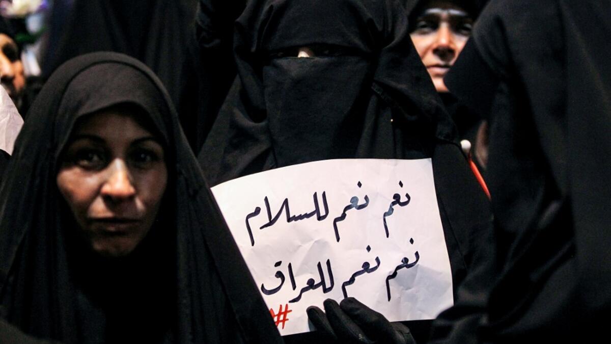 An Iraqi woman holds up a sign reading in Arabic "yes, yes to peace, yes, yes to Iraq" as she demonstrates with other followers of Shiite Muslim cleric Moqtada al-Sadr in the capital Baghdad's central Tahrir Square late on May 24, 2019, against involvement in any conflict between Iran and the United States.  AHMAD AL-RUBAYE / AFP