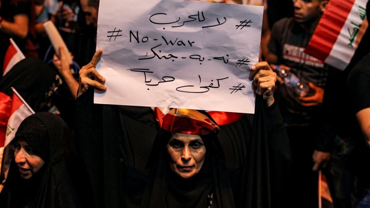 An Iraqi woman holds up a sign reading in Arabic, English, and Farsi "No to war" as she demonstrates with other followers of Shiite Muslim cleric Moqtada al-Sadr in the capital Baghdad's central Tahrir Square late on May 24, 2019, against involvement in any conflict between Iran and the United States.  AHMAD AL-RUBAYE / AFP
