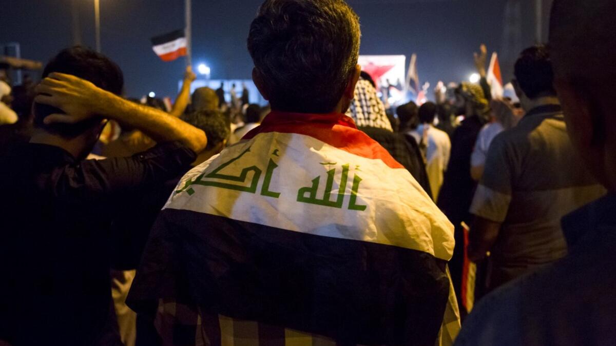 An Iraqi follower of Shiite Muslim cleric Moqtada al-Sadr stands wearing a national flag around his shoulders while demonstrating in the southern city of Basra on May 24, 2019, against involvement in any conflict between Iran and the United States.  Hussein FALEH / AFP