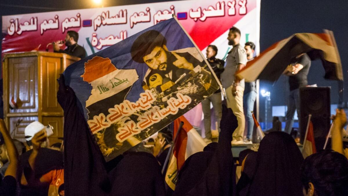 Iraqi followers of Shiite Muslim cleric Moqtada al-Sadr wave national flags and raise protest signs as they demonstrate in the southern city of Basra on May 24, 2019, against involvement in any conflict between Iran and the United States.  Hussein FALEH / AFP