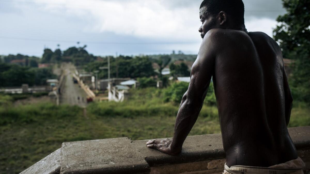 An inhabitant waits in front of the abandoned hospital of the roca Agostinho Neto, an abandoned cocoa plantation of Sao Tome and Principe, on May 12, 2019.  Alexis HUGUET / AFP