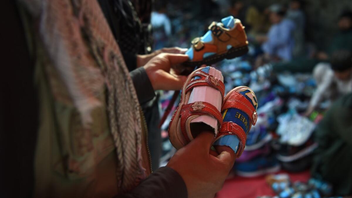 An Afghan man looks at sandals for children ahead of the Eid al-Fitr festival, which marks the end of Islamic holy month of Ramadan, at a roadside in Kabul on June 2, 2019. WAKIL KOHSAR / AFP