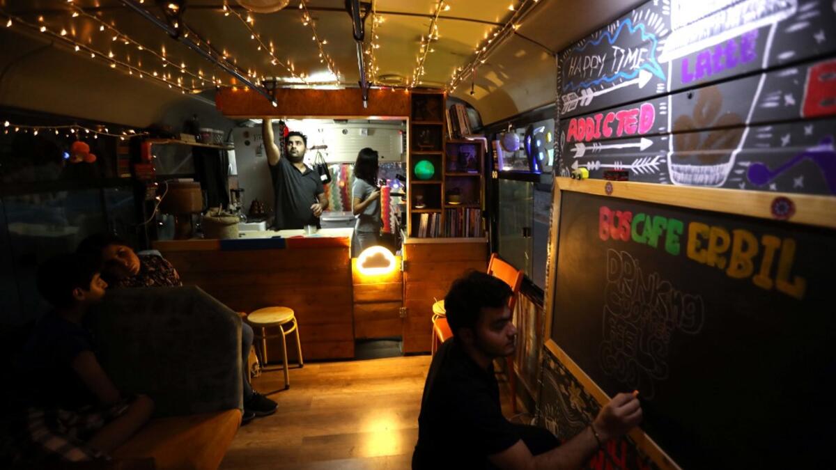 Young Iraqi Kurds work inside "The Bus Cafe Erbil" in Arbil, the capital of Iraq's Kurdish autonomous region, late on June 7, 2019, on the long weekend of the Eid al-Fitr holiday which marks the end of the Muslim holy month of Ramadan.  SAFIN HAMED / AFP