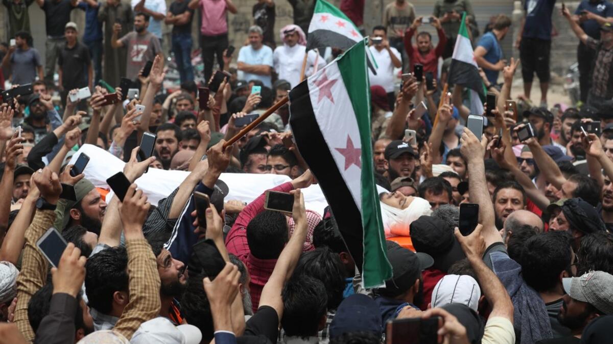 A picture taken on June 9, 2019 shows Syrians waving rebel flags during the funeral of late rebel fighter Abdel-Basset al-Sarout in al-Dana in Syria's jihadist-controlled Idlib region, near the border with Turkey. OMAR HAJ KADOUR / AFP