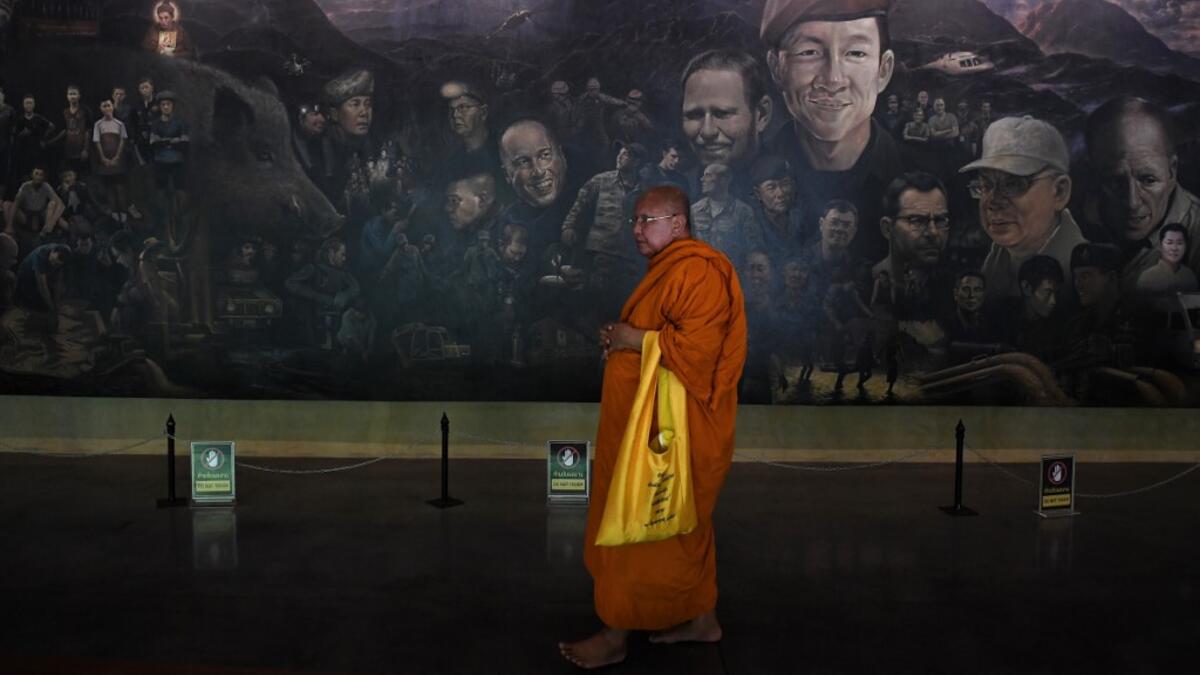 Tourists snap selfies by a bronze statue of the diver who died trying to save the 'Wild Boar' footballers from a flooded cave, while momentos from their rescue fly off the shelves -- scooped up by the 1.3 million people who have descended on a once serene mountainside in northern Thailand. Lillian SUWANRUMPHA / AFP
