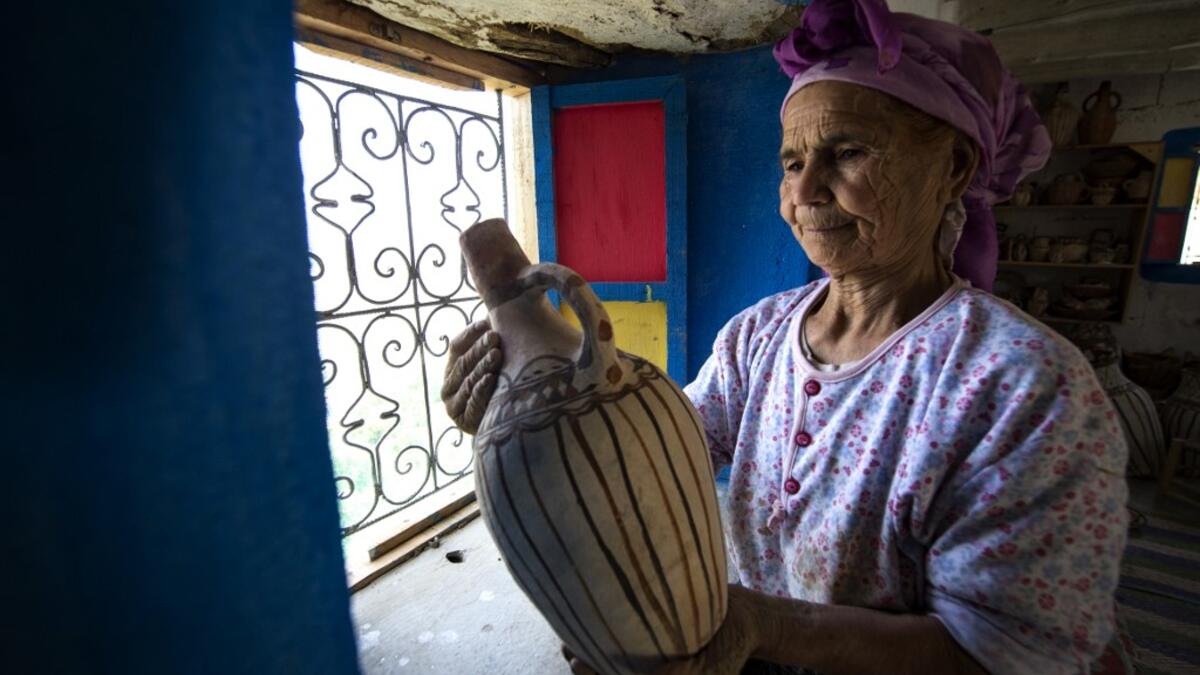 Moroccan potter Aicha Tabiz, also known as Mama Aicha, holds one of her works near the village of Ourtzagh in the foothills of the Rif mountains on June 12, 2019. Like everywhere in the Rif mountains, women potters from the Sless tribe, to which Aicha Tabiz's family belongs, are vanishing.  The tribe counted around 90 potters at the end of 1990s. Now, only a half-dozen remain.   FADEL SENNA / AFP