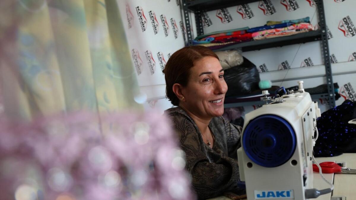 Iraq's Yazidi seamstress Shirin Ghaliyeh, 39, smiles while working at her shop in the Khonke camp for displaced persons in northwestern Iraq on June 24, 2019. SAFIN HAMED / AFP