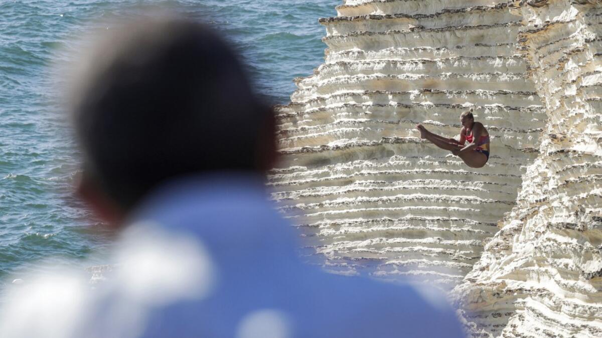 A cliff diver jumps from a platform on the landmark Raouche sea rock off the coast of the Lebanese capital Beirut on July 14, 2019, during the women's 2019 Red Bull Cliff Diving World Series.  ANWAR AMRO / AA / AFP