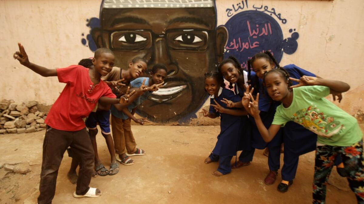 Pupils gesture in front of a mural painting of a protester killed during anti-government protests in the Sudanese capital Khartoum on July 22, 2019.  ASHRAF SHAZLY / AFP