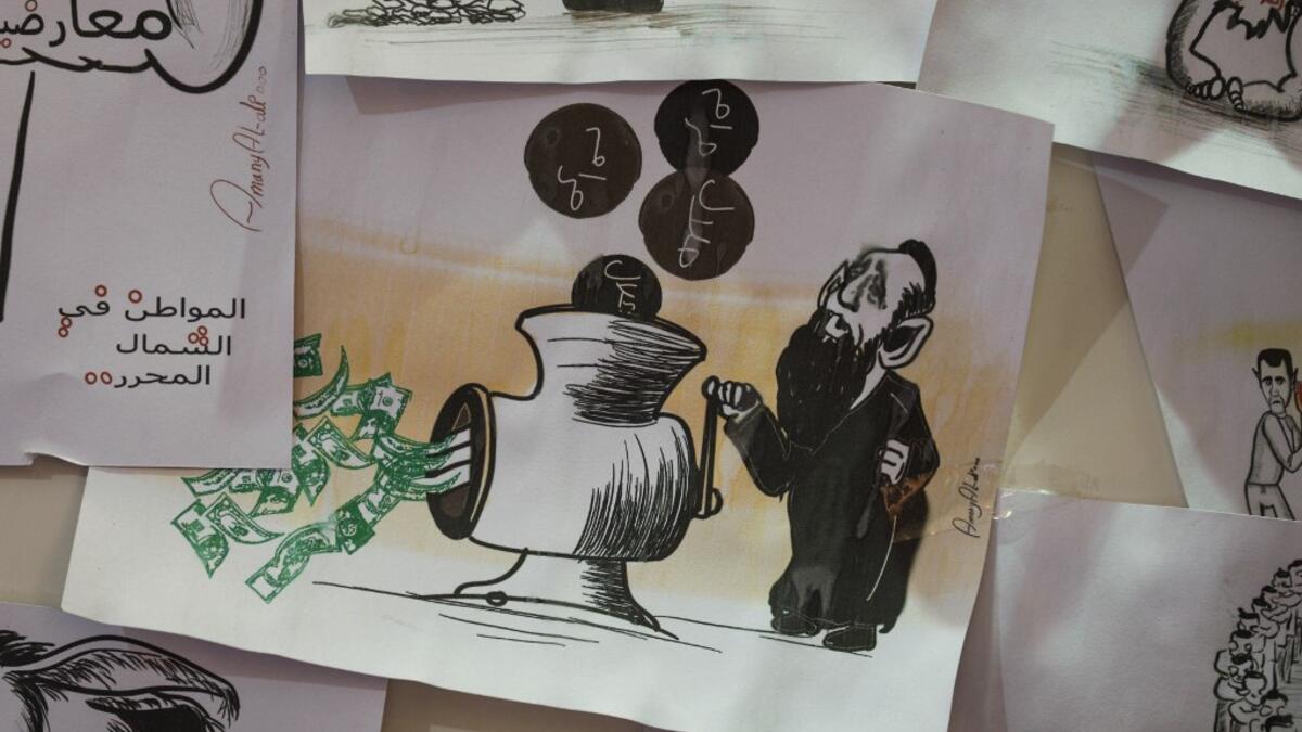 This picture taken on June 16, 2019, shows various illustrations by Syrian Cartoonist Amani al-Ali at her home studio in the city of Idlib in the eponymous northwestern province.  Omar HAJ KADOUR / AFP