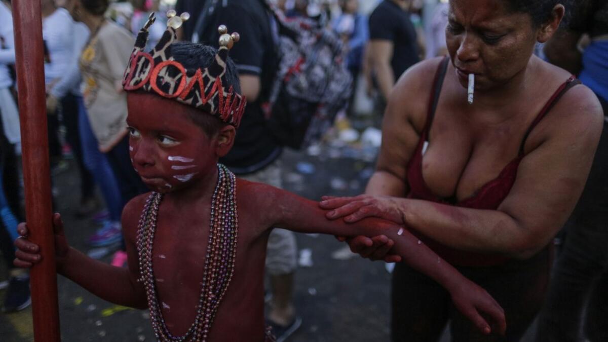 A catholic faithful woman paints her son with floor painture during the opening of the ten-day celebration of the Santo Domingo de Guzman festival in Managua, on August 1, 2019.  INTI OCON / AFP