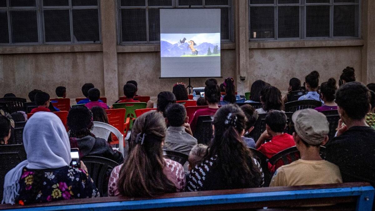 Children attend a film screening as part of the mobile cinema "Komina Film" initiative organised by Syrian-Kurdish filmmaker Shero Hinde, at a school yard in the village of Shaghir Bazar, 55 kilometres southest of Qamishli in the Kurdish-populated areas of northeastern Syria's Hasakeh province, on July 28, 2019.  DELIL SOULEIMAN / AFP