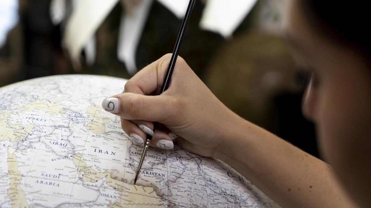 An artist applies paintwork to a globe at the Bellerby and Co Globemakers' workshop and headquarters in Stoke Newington in north London, on July 19, 2019. Niklas HALLE'N / AFP