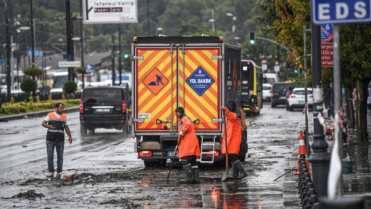Municipality employees work on the road in Eminonu district, Istanbul, after a heavy rainfall, on August 17, 2019. Turkey's mega city Istanbul was lashed by a heavy rainstorm on August 17, killing a homeless man and leaving parts of the historic Grand Bazaar flooded.  Ozan KOSE / AFP