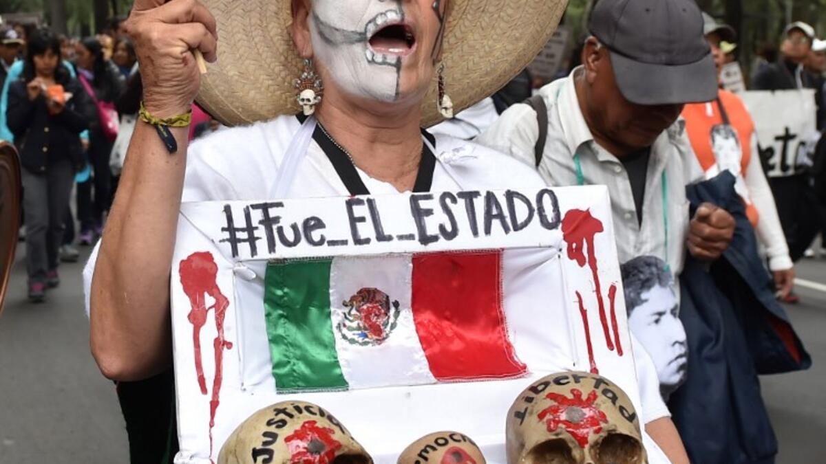 In this file photo taken on September 26, 2015 Mexican activist Julia Klug holds a fake coffin with skulls captioned "Justice, Democracy and Freedom" and a sign reading "It was the State" during a protest in Mexico City, commemorating the first anniversary of the disappearance of the Ayotzinapa students. Yuri CORTEZ / AFP