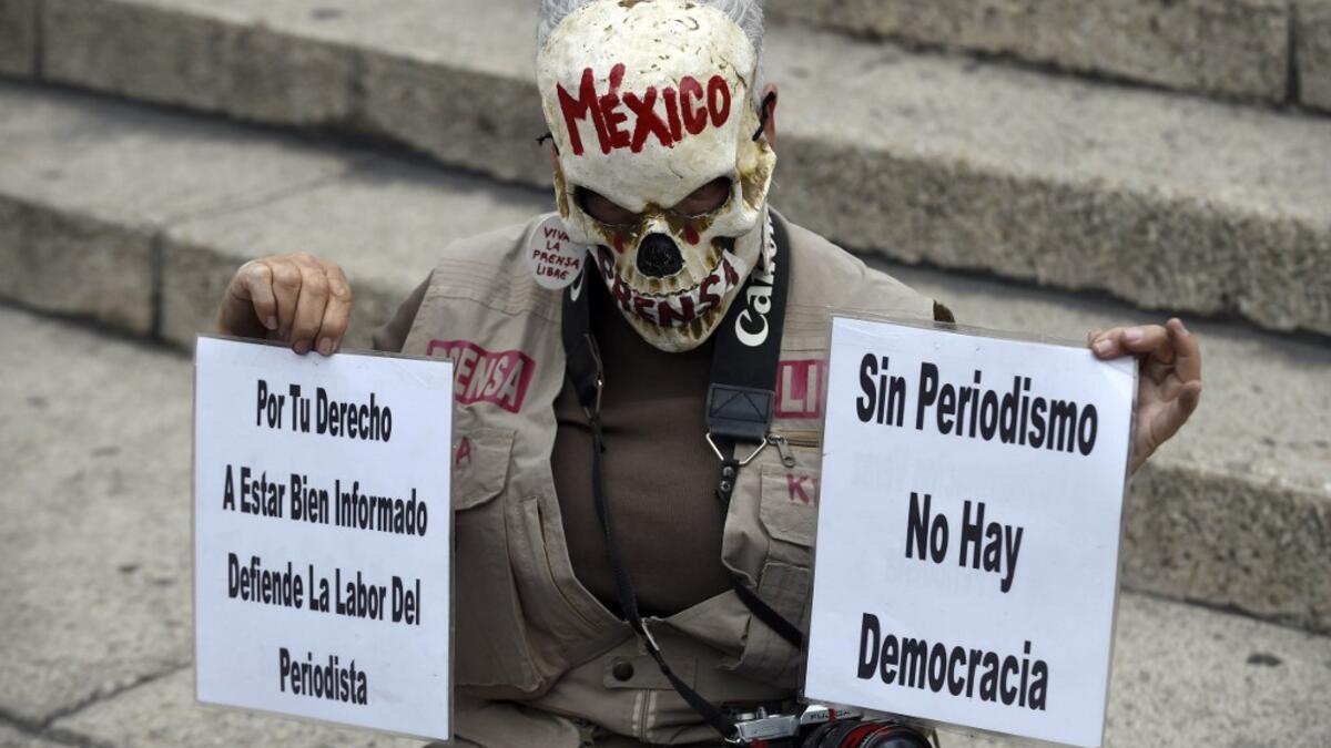 In this file photo taken on March 25, 2017 Mexican activist Julia Klug holds signs reading "For your right to be well informed, defend the journalist's work" and "Without journalism there is no democracy" during a protest against the murder of Mexican journalist Miroslava Breach, in Mexico City. ALFREDO ESTRELLA / AFP
