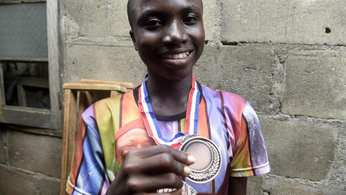 Fourteen-year-old mechanic Jamiu Ninilowo holds a medal he won following a chess tournament at Ogolonto in Ikorodu district of Lagos, on August 17, 2019. In front of chess boards in Lagos, children are busy, concentrating.  PIUS UTOMI EKPEI / AFP