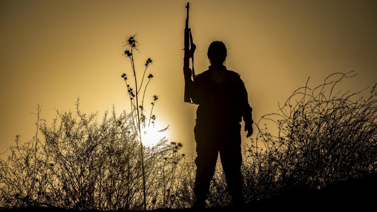 A member of the Bethnahrin Women Protection Forces (HSNB), an all-female Syriac-Assyrian paramilitary group under the umbrella of the Syrian Democratic Forces (SDF), stands holding up a Kalashnikov assault rilfe during a commemoration of the fourth anniversary of their creation, in the countryside of the town of Tall Tamr in the northwestern Syrian province of Hasakah, on August 30, 2019.  Delil SOULEIMAN / AFP