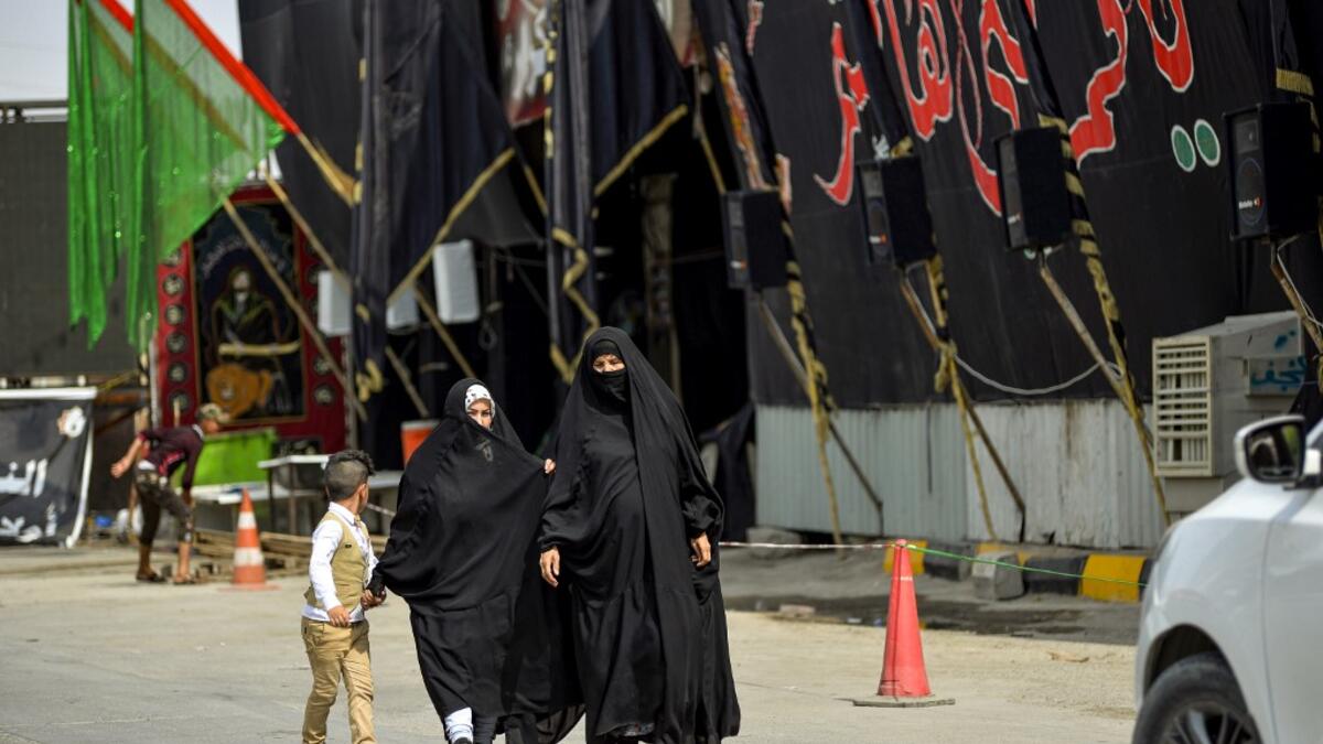 Women walk past a mourning tent erected amidst preparations ahead of the Shiite Muslim religious mourning period of Ashura, in the central Iraqi holy shrine city of Najaf on August 31, 2019.  Haidar HAMDANI / AFP