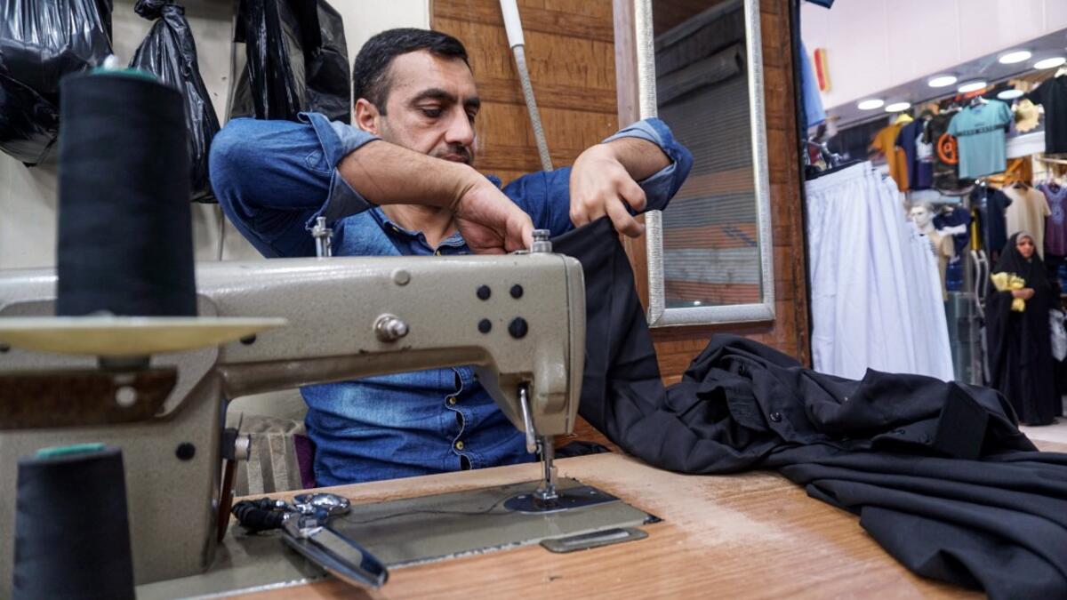 A man sews together black garbs to be sold to Shiite Muslim pilgrims amidst preparations ahead of the Shiite religious mourning period of Ashura, in the central Iraqi holy shrine city of Najaf on August 31, 2019.  Haidar HAMDANI / AFP