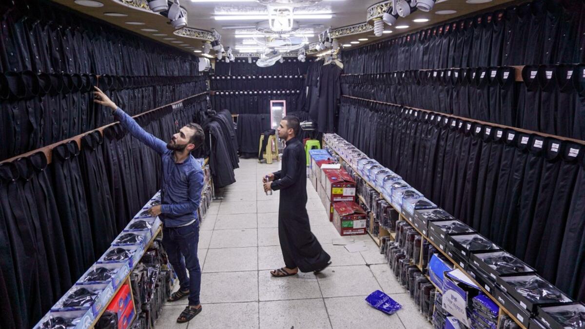 A man browses black garbs sold to Shiite Muslim pilgrims amidst preparations ahead of the Shiite religious mourning period of Ashura, in the central Iraqi holy shrine city of Najaf on August 31, 2019.  Haidar HAMDANI / AFP