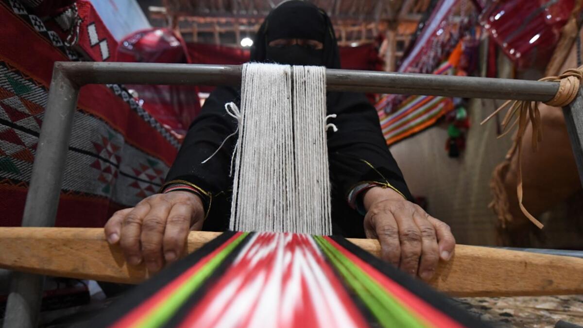 An Emirati woman works on a loom in a display of traditional crafts on the first day of the Abu Dhabi International Hunting and Equestrian exhibition (ADIHEX) in the UAE capital on August 31, 2019.  KARIM SAHIB / AFP