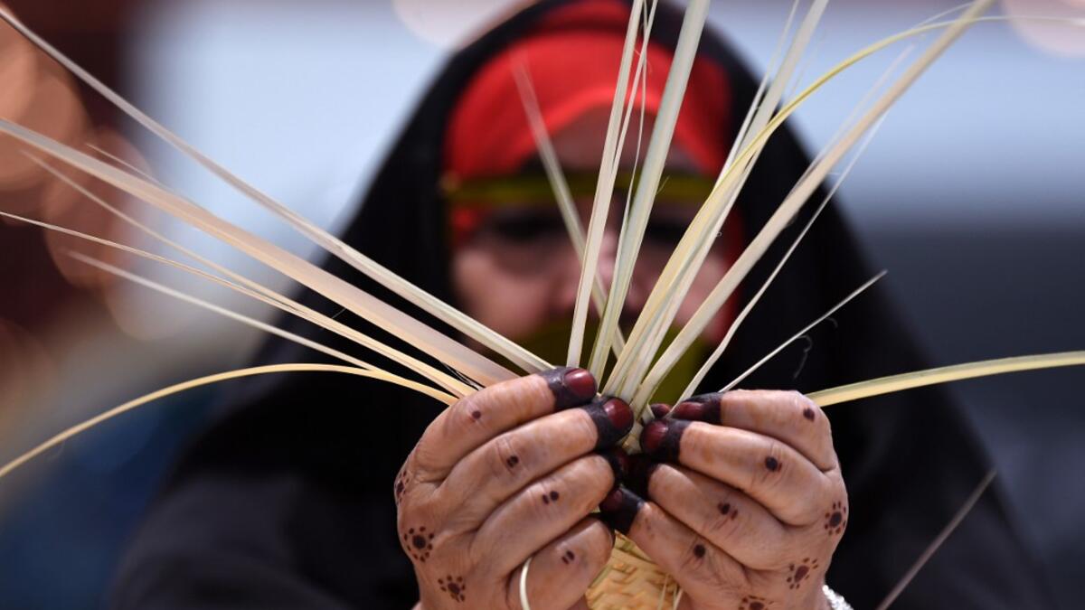 An Emirati woman knits together straw leaves in a display of traditional crafts on the first day of the Abu Dhabi International Hunting and Equestrian exhibition (ADIHEX) in the UAE capital on August 31, 2019.  KARIM SAHIB / AF