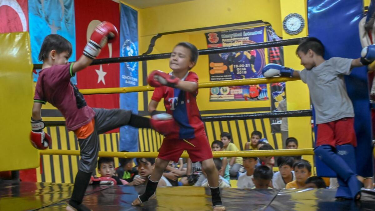 In this photograph taken on August 29, 2019, children from Muslim Uighur minority take part in a training boxing match as a trainer and children watch in Istanbul. BULENT KILIC / AFP