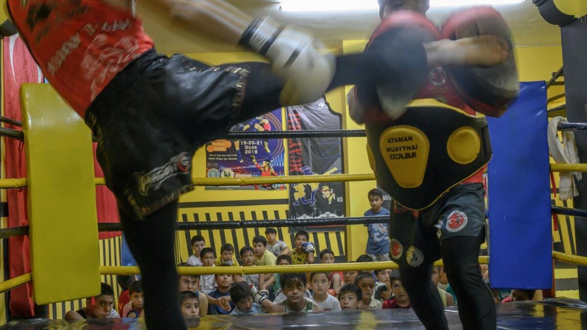 In this photograph taken on August 29, 2019, Muay Thai boxer practices with a trainer as children from Muslim Uighur minority watch in Istanbul. BULENT KILIC / AFP