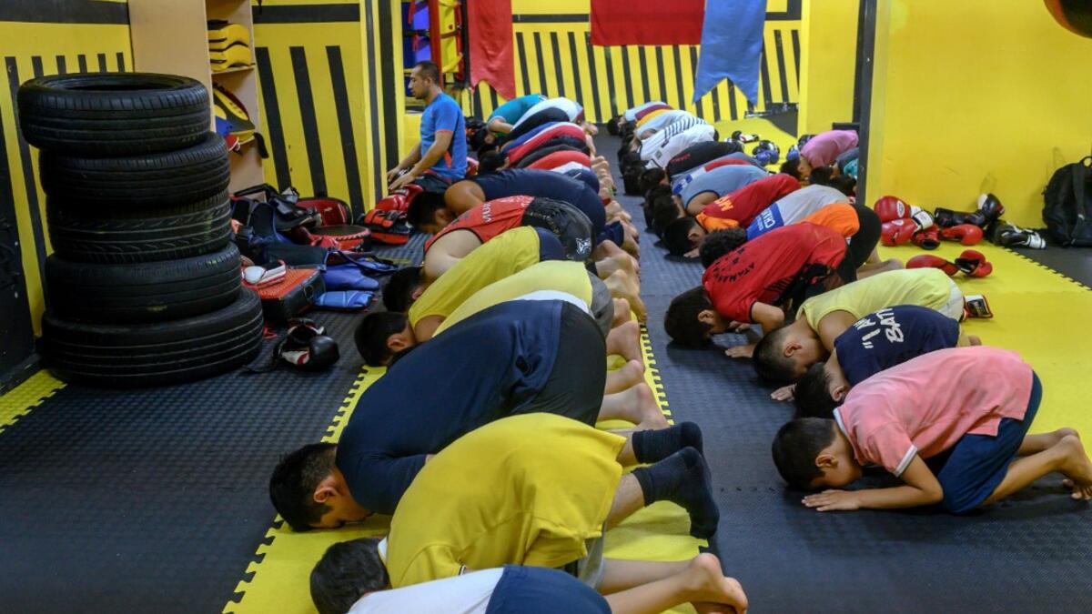 In this photograph taken on August 29, 2019, trainers and children from Muslim Uighur minority pray as they attend a Muay Thai training session in a boxing academy in Istanbul. BULENT KILIC / AFP