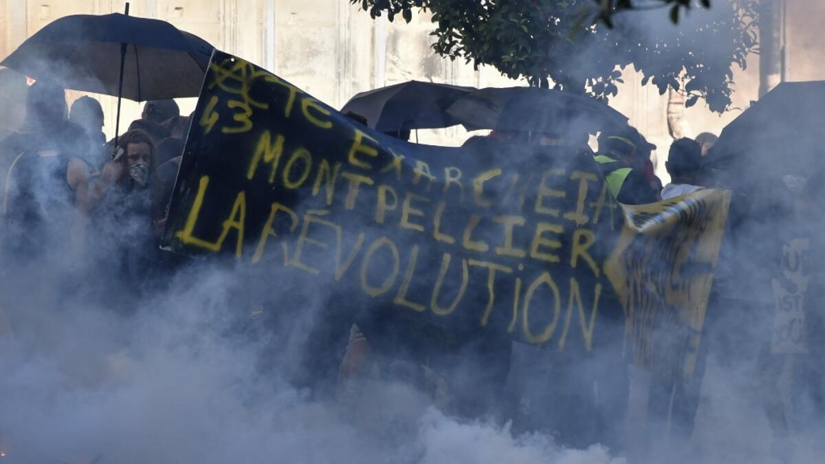 Protesters stand amid smoke from tear gas and behind a banner reading "Montpellier, Hong Kong, the international revolution" during an anti-government demonstration called by the "Yellow Vests" (Gilets Jaunes) movement on September 7, 2019 in Montpellier, southern France. Pascal GUYOT / AFP