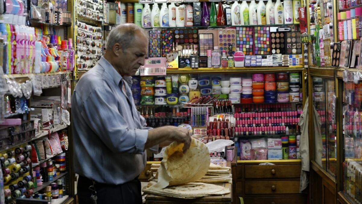 A merchant prepares lunch inside his shop at the Bzourieh market in the centre of the Syrian capital Damascus . The declining value of the pound is a sure sign of Syria's ailing economy. LOUAI BESHARA / AFP