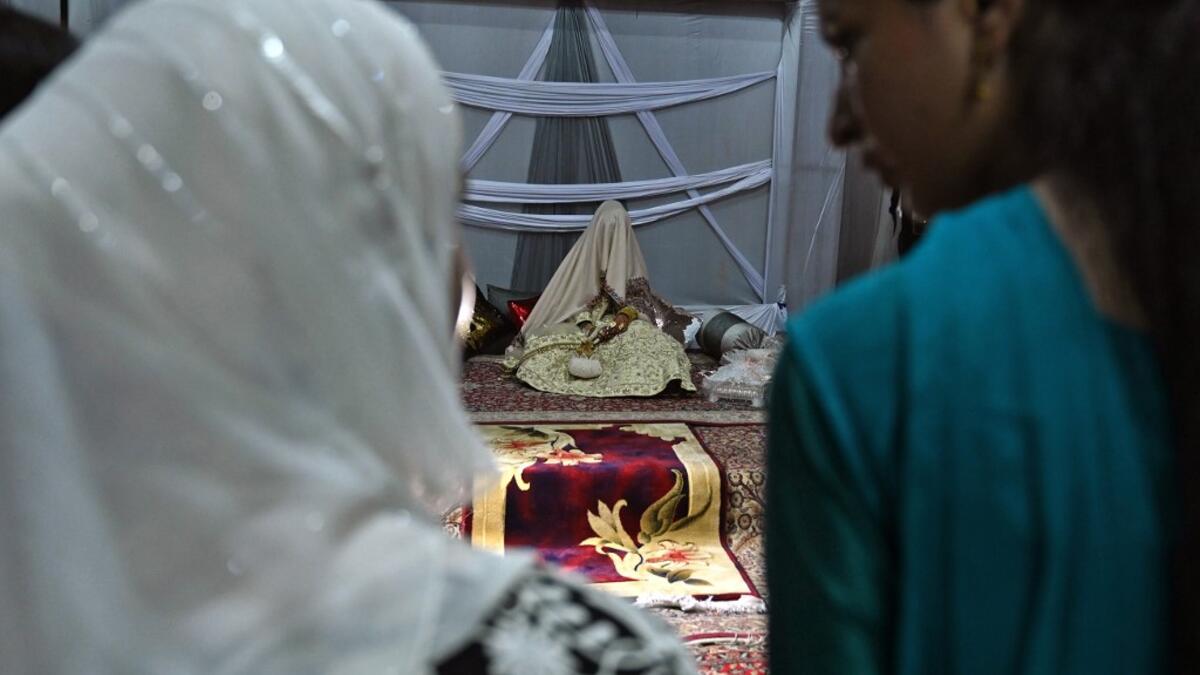 In this photo taken on September 15, 2019, guests look at a bride (C) with her face and body covered with a shawl sits in her new husband's home following their marriage in Kashmir's Baramulla district, north of Srinagar. TAUSEEF MUSTAFA / AFP
