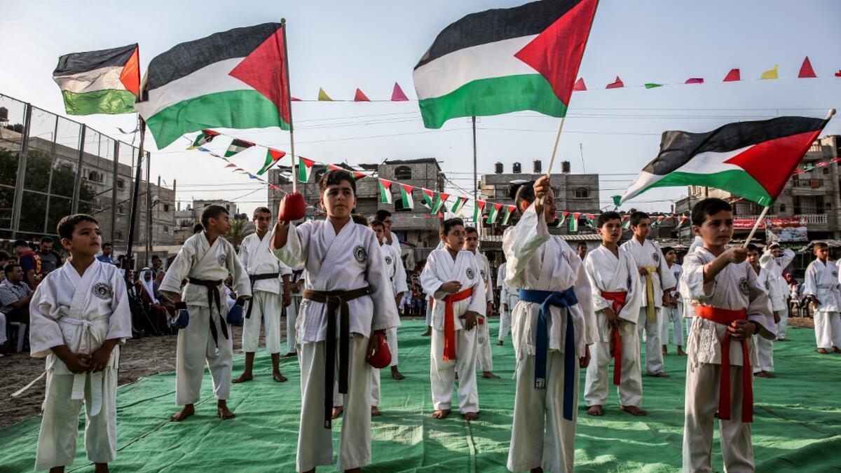 Young Palestinian karatekas wave Palestinian flags during a Karate promotion ceremony at a sporting centre in the Rafah camp for Palestinian refugees in the southern Gaza Strip on September 20, 2019. SAID KHATIB / AFP