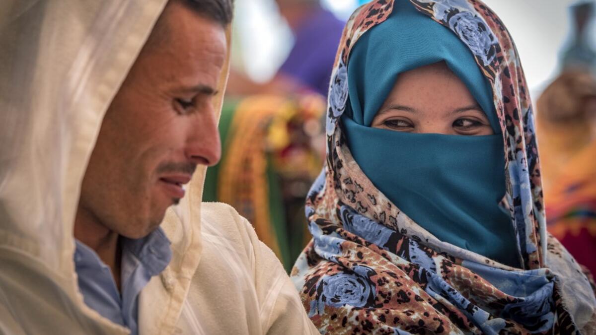 A young Amazigh (Berber) couple smile at each other as they wait for their wedding ceremony during the annual "Engagement Moussem" festival near the village of Imilchil in central Morocco's high Atlas Mountains on September 21, 2019. Each year in the High Atlas Mountains hamlet of Ait Amer, tribes celebrate with dances and music, the collective wedding of young Amazigh couples during the traditional festival of "Engagement Moussem". FADEL SENNA / AFP