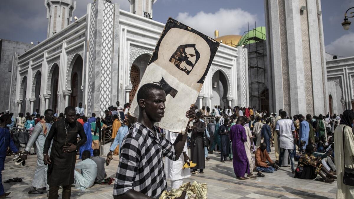 A worshipper holds a poster of Sante Serigne Touba Mbacke while waiting outside the Great Mosque of the Mourides on September 27, 2019 in Dakar, ahead of its inauguration. Senegal's influential Mouride Brotherhood will inaugurate a 30,000-capacity mosque in the capital Dakar, said to be the largest in West Africa. JOHN WESSELS / AFP