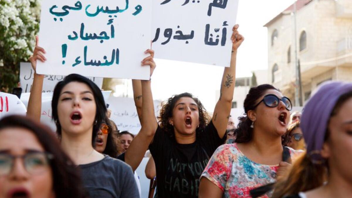 Arabic slogans on placards call for an end to violence against women and introducing a law for family protection against domestic violence."  (Twitter)