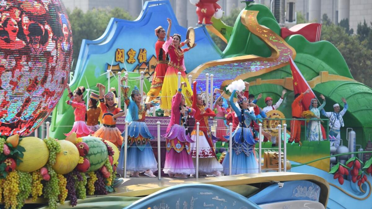 Performers stand on the Xinjiang region float as it passes by Tiananmen Square during the National Day parade in Beijing on October 1, 2019, to mark the 70th anniversary of the founding of the People's Republic of China. GREG BAKER / AFP