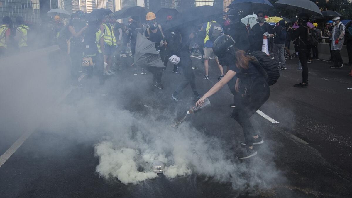 A protester pours water on a tear gas cannister fired by police beside the Admiralty MTR station in Hong Kong on October 1, 2019, as the city observes the National Day holiday to mark the 70th anniversary of communist China's founding. Mark RALSTON / AFP