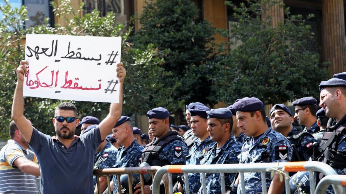 A Lebanese protester holds a placard reading in Arabic "Down with the regime, down with the government" during a demonstration in central Beirut's Martyr Square on October 6, 2019. Lebanese protested in the capital over increasingly difficult living conditions, amid fears of a dollar shortage and possible price hikes. ANWAR AMRO / AFP
