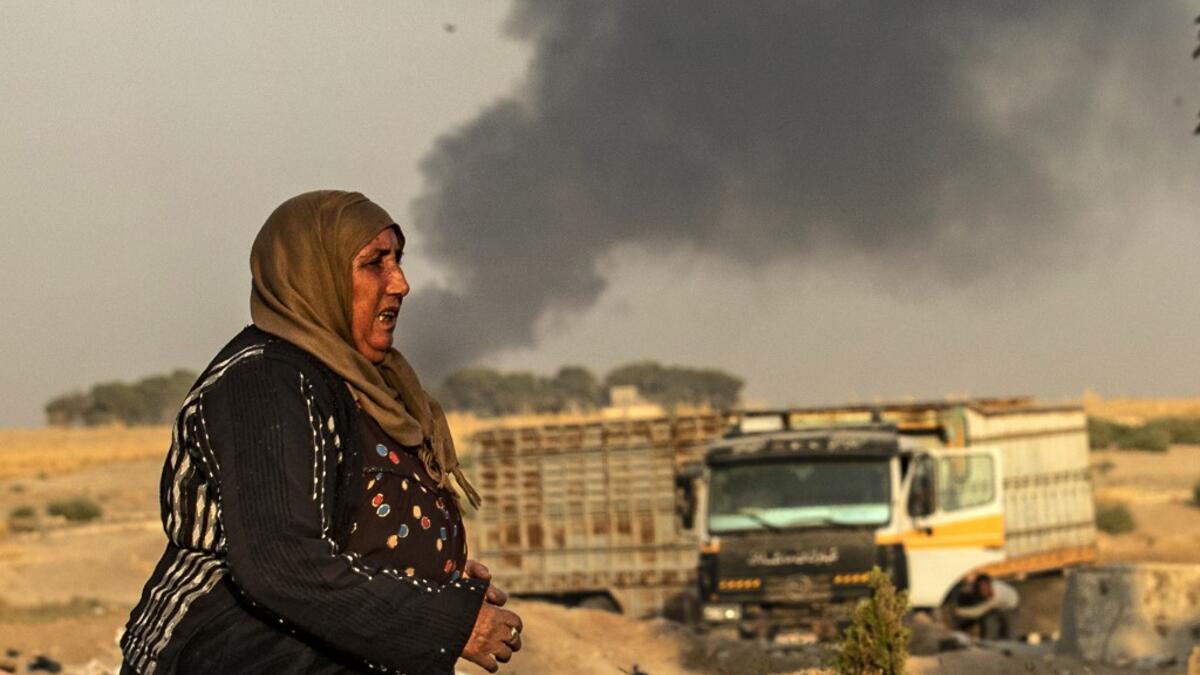 A woman walks as smoke billows following Turkish bombardment in Syria's northeastern town of Ras al-Ain in the Hasakeh province along the Turkish border on October 9, 2019. Turkey launched an assault on Kurdish forces in northern Syria with air strikes and explosions reported along the border. President Recep Tayyip Erdogan announced the start of the attack on Twitter, labelling it "Operation Peace Spring".  Delil SOULEIMAN / AFP