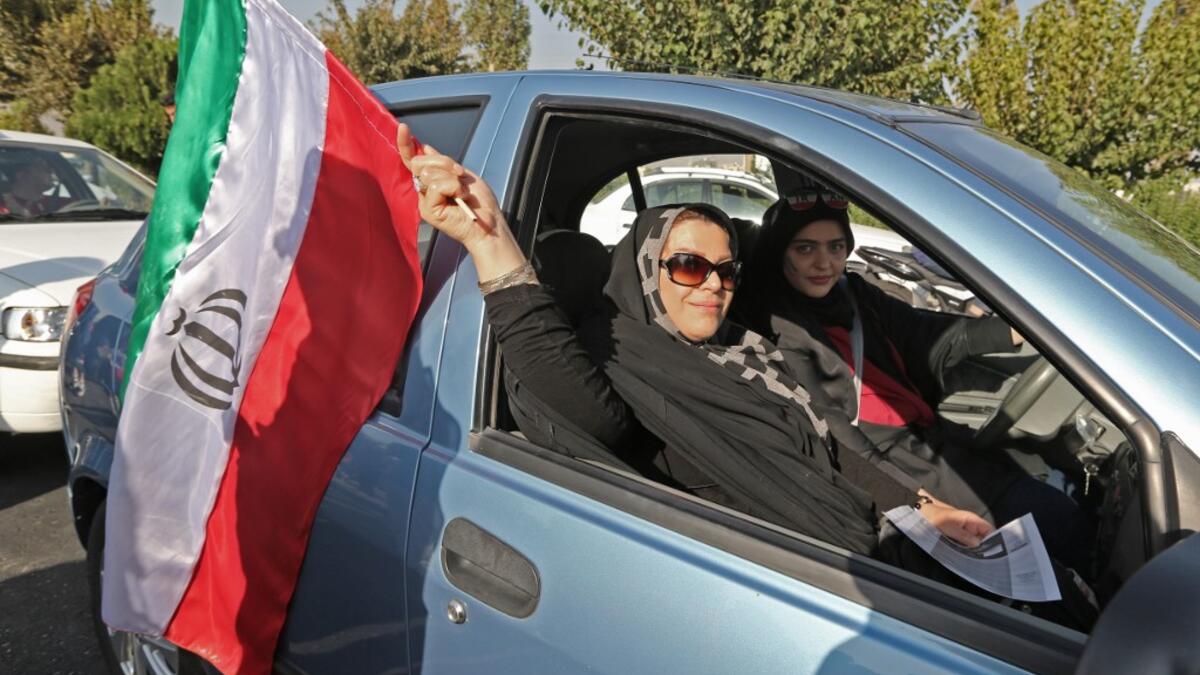 Iranian women wave their country's national flag as they arrive at the Azadi stadium in the capital Tehran ahead of the World Cup Qatar 2022 Group C qualification football match between Iran and Cambodia on October 10, 2019.ATTA KENARE / AFP