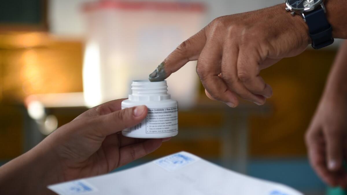 A Tunisian voter dips his finger in ink after casting his ballot at a polling station in the capital Tunis on October 13, 2019 during the second round of the presidential election. Tunisians began voting today in a presidential runoff pitting conservative law professor Kais Saied against media magnate Nabil Karoui, who was released from prison just days earlier. FETHI BELAID / AFP