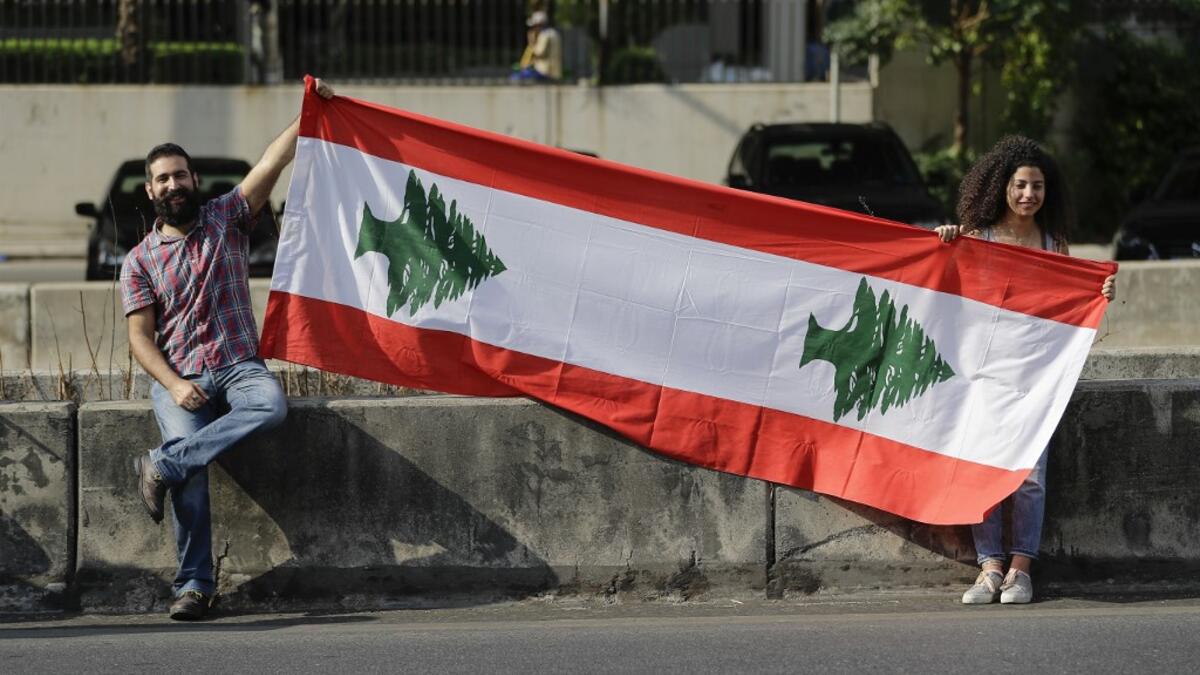 Lebanese protesters hold a national flag as they participate in forming a human chain along the coast from north to south as a symbol of unity, during ongoing anti-government demonstrations in Nahr al-Kalb north of Lebanon's capital Beirut on October 27, 2019. JOSEPH EID / AFP