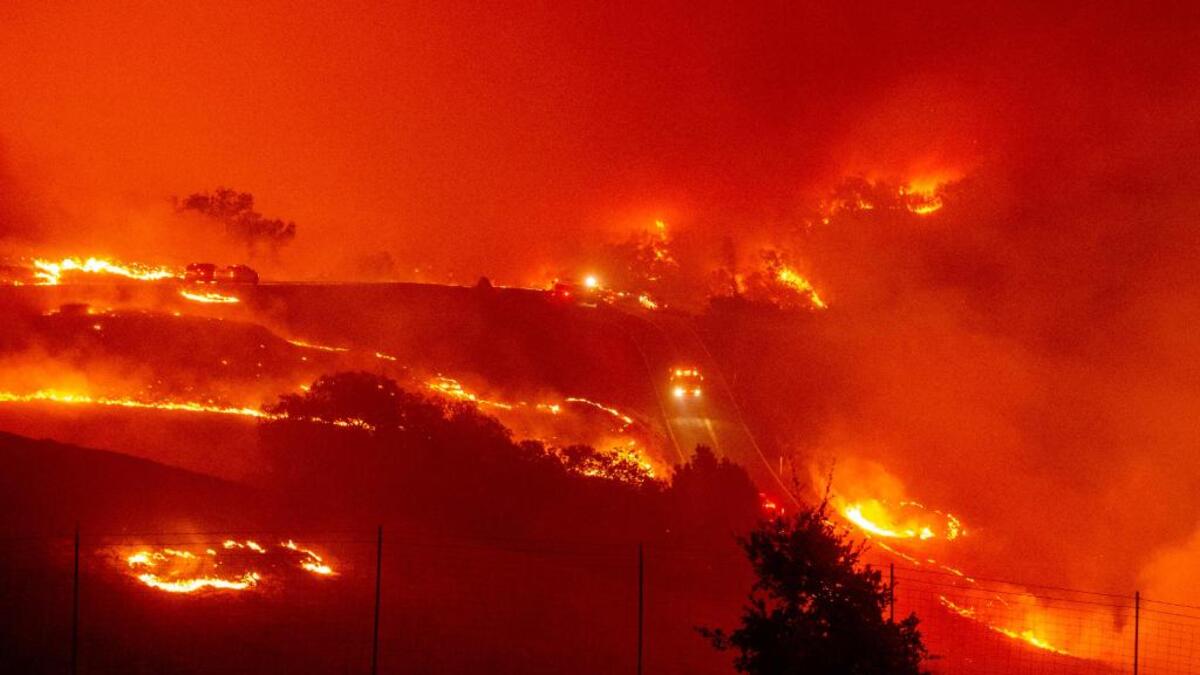 Fire trucks navigate roads surrounded with fire as wind and embers rip through the area during the Kincade fire near Geyserville, California. (Photo by Josh Edelson / AFP)