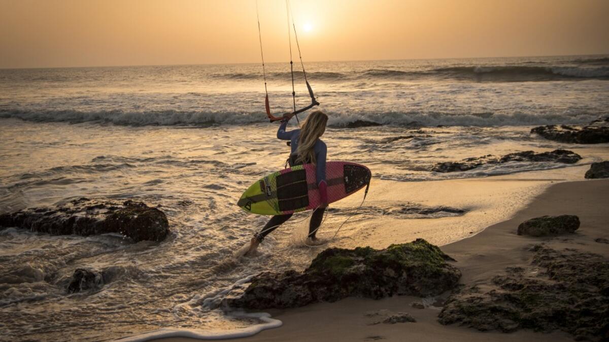 A picture taken on October 10, 2019, shows a kitesurfer holding her kite as she walks away at Dakhla beach in Morocco-administered Western Sahara. In the heart of disputed Western Sahara, a former garrison town has become an unlikely tourist magnet after kitesurfers discovered the windswept desert coast on the Atlantic is perfect for their sport. FADEL SENNA / AFP